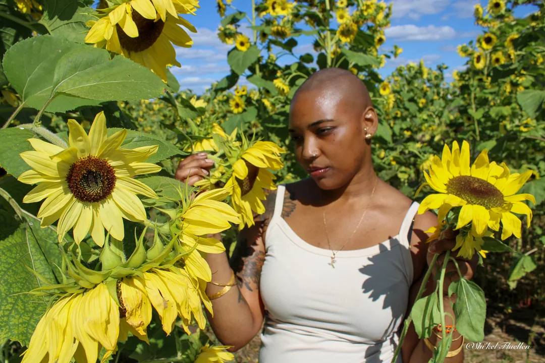 Woman standing among tall sunflowers in bright daylight